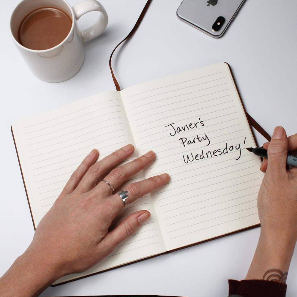 Vegan leather journal with handwritten notes and elastic closure.