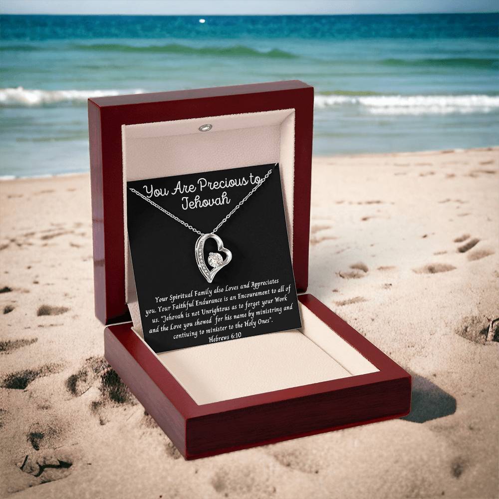 "You Are Precious" heart necklace in white or yellow gold finish with CZ crystals, displayed in a luxury gift box by the beach.