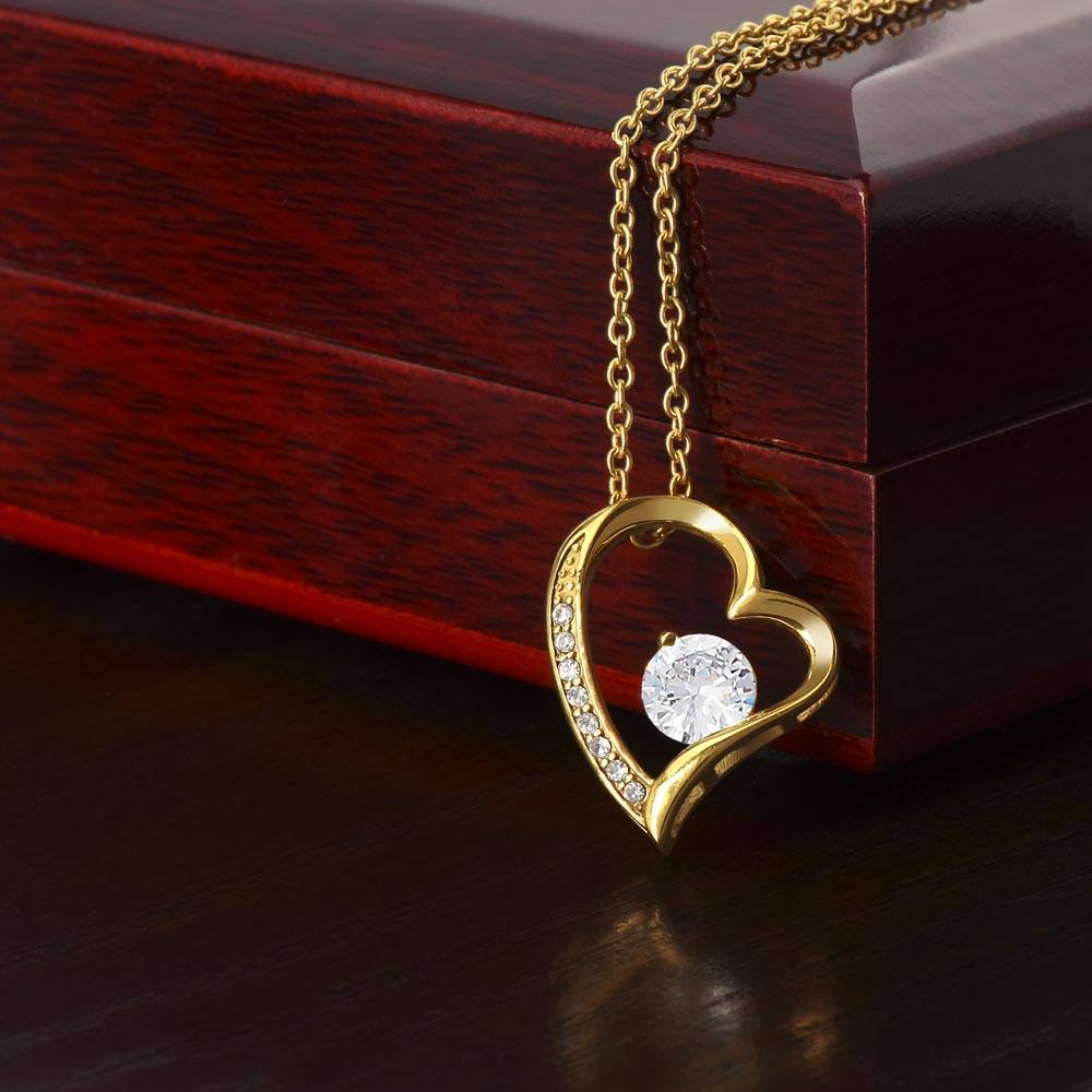 Gold heart necklace with cubic zirconia, on wooden box.