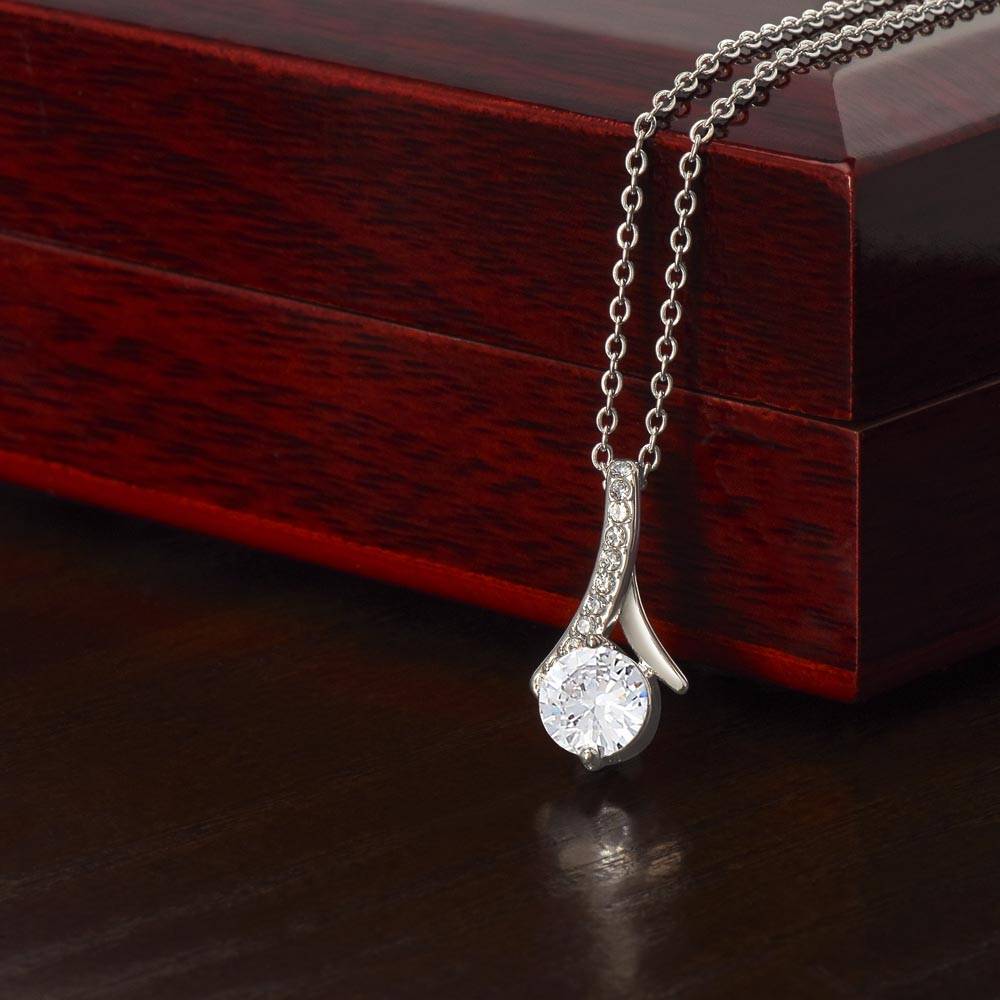 White or yellow gold finish necklace with cubic zirconia, ribbon-shaped pendant, mahogany box.