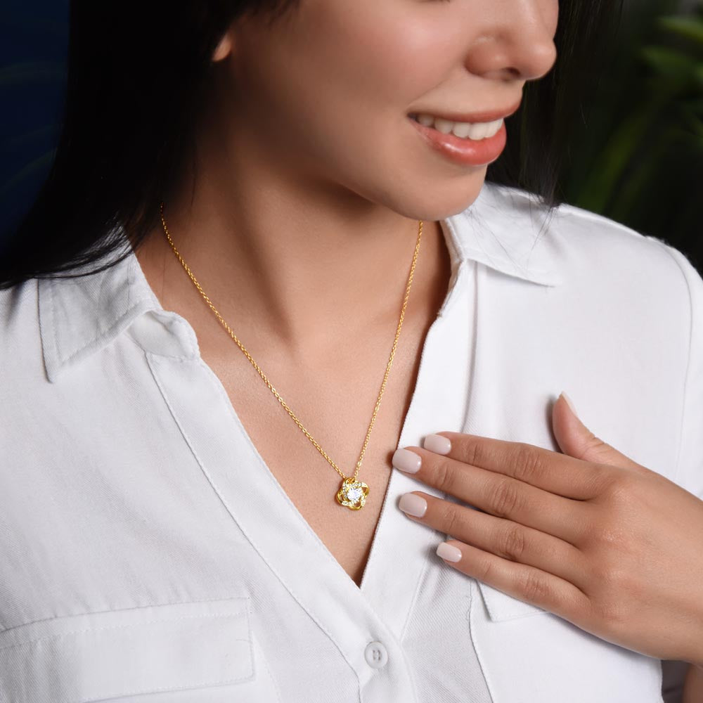 Woman wearing Love Knot Necklace with cubic zirconia pendant on a gold chain.