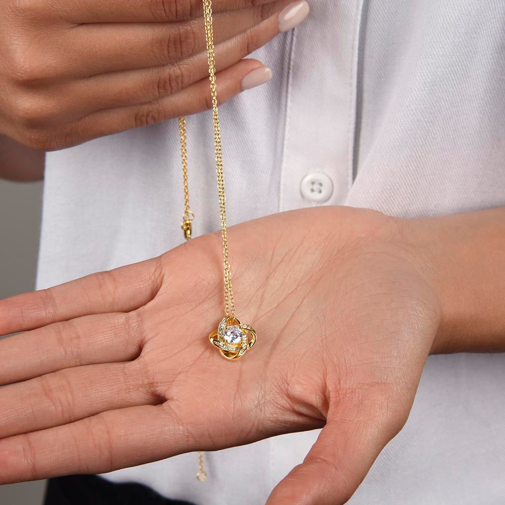 Love Knot Necklace with cubic zirconia pendant on a woman's hand.