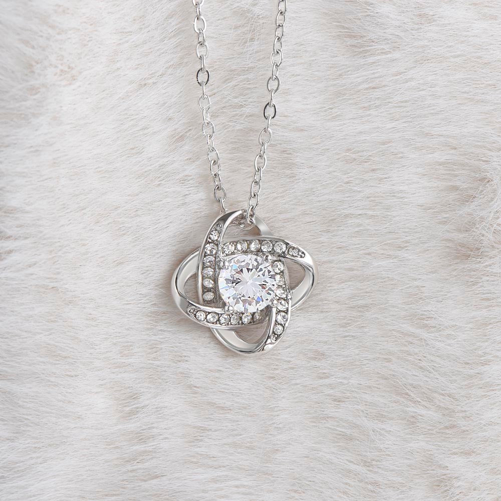 Love Knot Necklace with cubic zirconia pendant on a soft fur background.