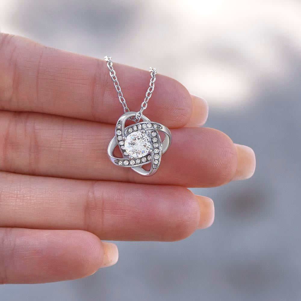 Love Knot Necklace with cubic zirconia pendant held in hand.