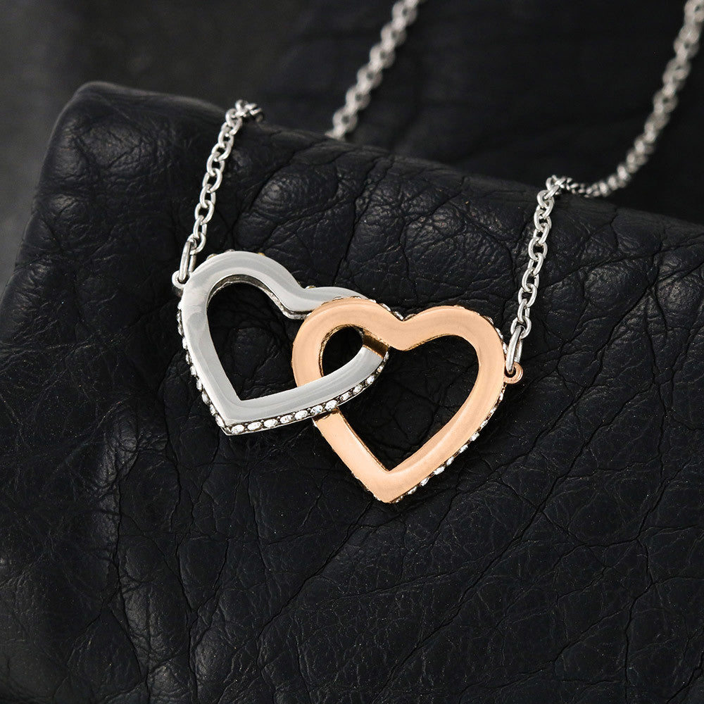 Interlocking hearts necklace with rose gold and silver finish on black background.