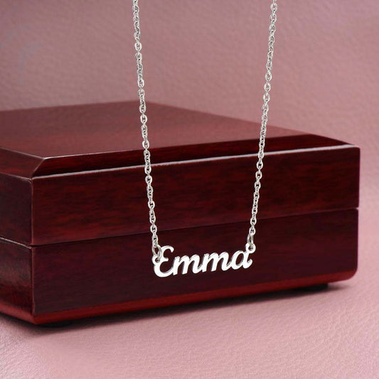 Customized name necklace in stainless steel with cursive design on a jewelry box.