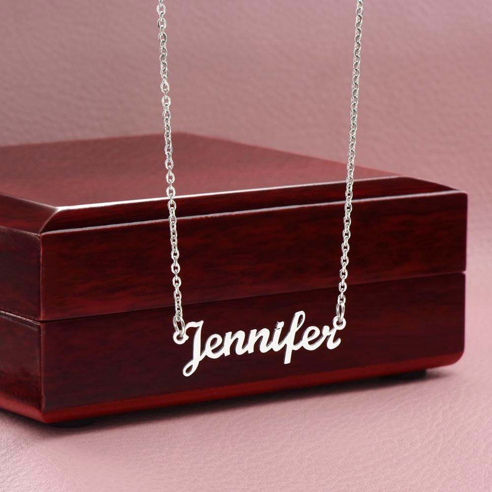 Customized name necklace in polished stainless steel on wood box, featuring adjustable cable chain.