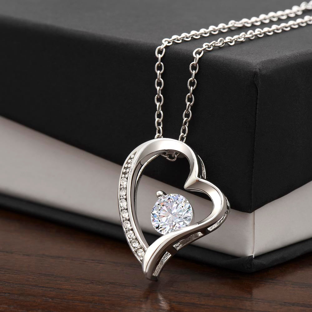 Heart-shaped necklace with CZ crystal, white gold finish, personalized for sister, on box.