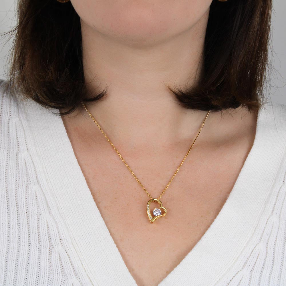 Woman wearing heart-shaped gold necklace with CZ crystal centerpiece.