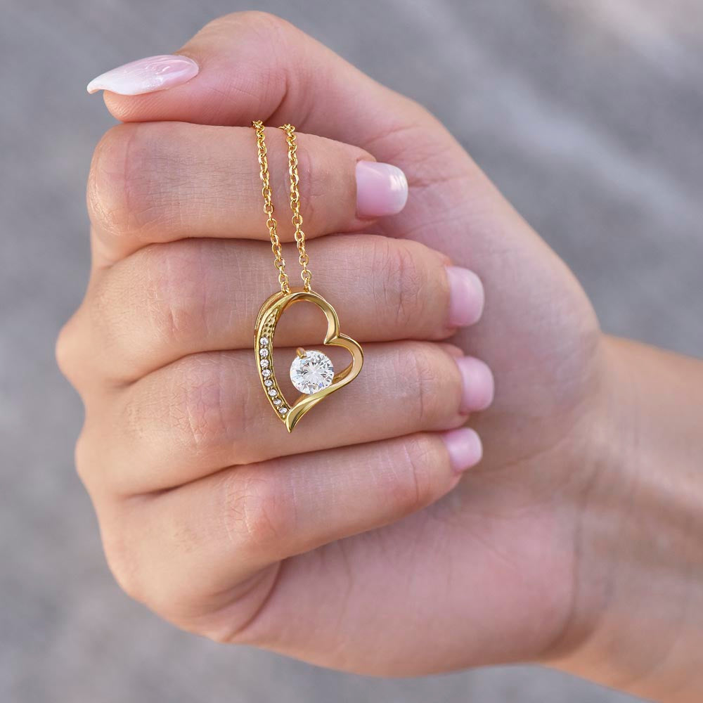 Heart-shaped gold necklace with central CZ crystal and smaller surrounding stones.