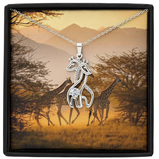 Giraffe hugging necklace in gold finish with cubic zirconia, displayed in an elegant box against a savanna background.