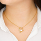 Heart pendant necklace with cubic zirconia, in yellow gold finish, worn around the neck.