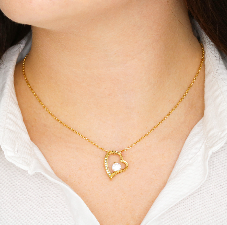 Heart pendant necklace with cubic zirconia, in yellow gold finish, worn around the neck.